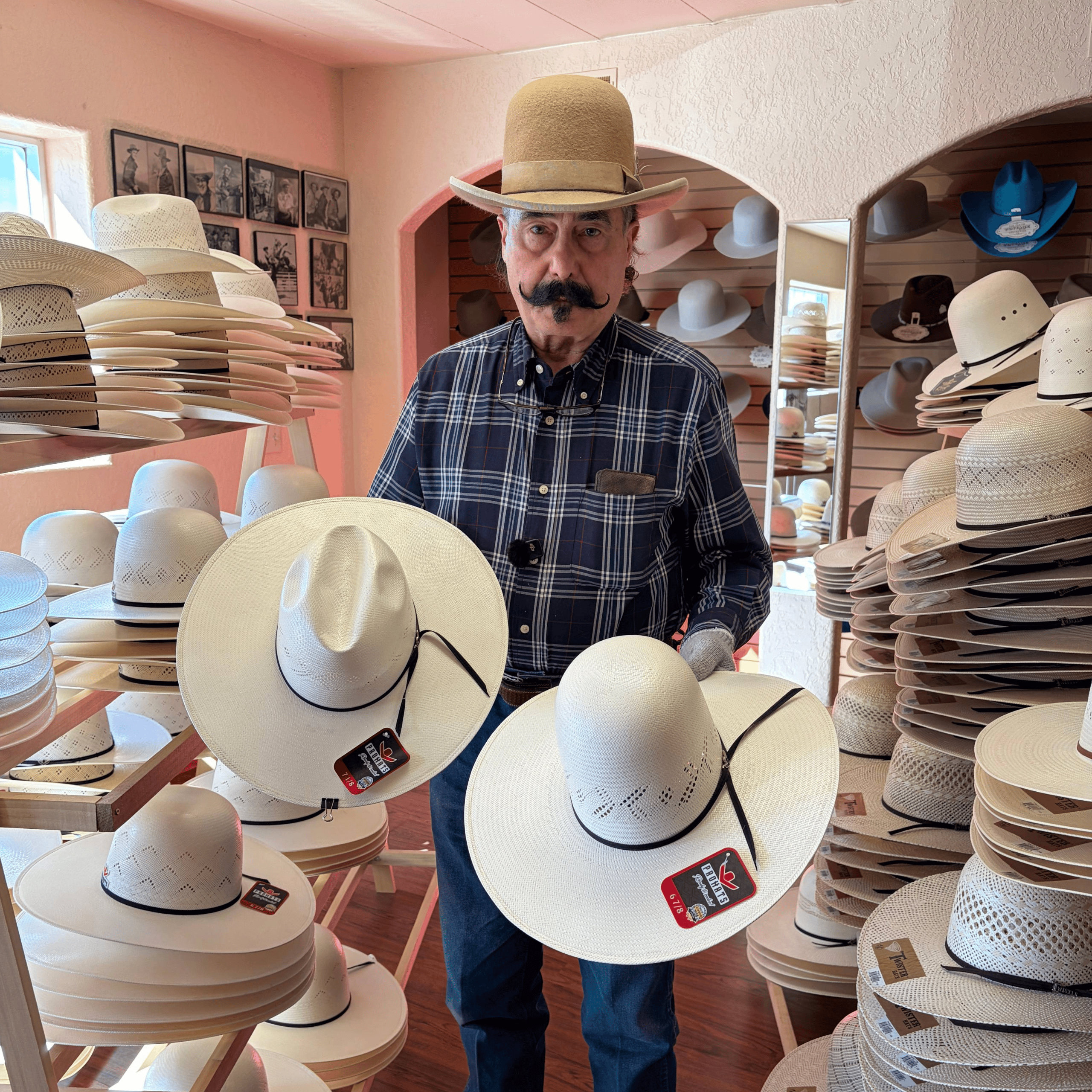 Hat maker Jack Scholl holding two ProHats straw hats, one in an open crown and another shaped in a Minnick style crown